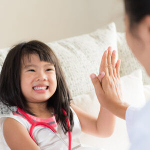 Happy little cute girl on consultation at the pediatrician. Girl is smiling and giving high five to doctor. Medicine and health care concept.