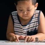 Young boy learns to save money by studying finance, collecting coins, and understanding the importance of investment and saving for children. boy, save, money, study, children, person, coin, finance.